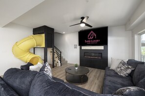Main Level: Living Room with 85" TV, fireplace, and play house with slide