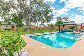 A large oak tree in the center of the yard with 2 hammocks 