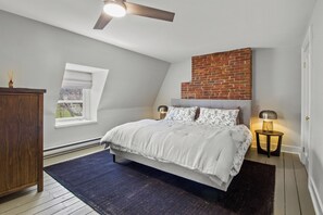 Experience the unique charm of this bedroom, featuring exposed brick accents, a plush king-sized bed, and a tranquil ambiance