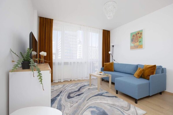 A bright space of a cosy saloon with a blue sofa bed.