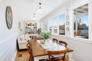 The light-filled dining area within the sunroom features a six-seater table with views looking out to the patio and backyard. 
