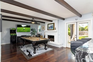 Game room with French doors leading to the 45' covered patio. Game room includes a pool table, golden tee arcade game, a poker set, and a big screen TV to watch your favorite sports