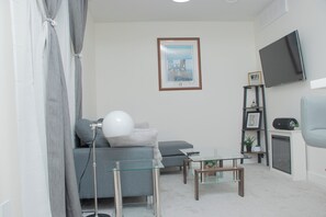 Living area with a comfy sofa, smart tv, bluetooth speaker and fire place