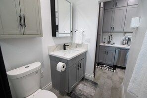 This modern bathroom features sleek gray cabinets and a pristine white toilet. 