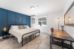 The primary bedroom features a king bed, workspace table, and an ensuite bath.