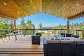 Soak in the beauty of nature on our spacious covered deck, featuring a wooden ceiling, comfortable outdoor seating, and a glass table. Overlooking stunning views of trees and water, it's the perfect spot for morning coffee or evening relaxation.