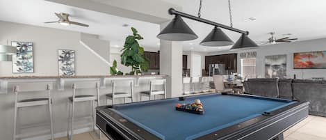 Enjoy endless fun in this stylish game room with a pool table and open kitchen, perfect for entertaining and relaxation.