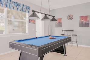 Enjoy a fun game night in this stylish game room with a pool table and cozy seating.