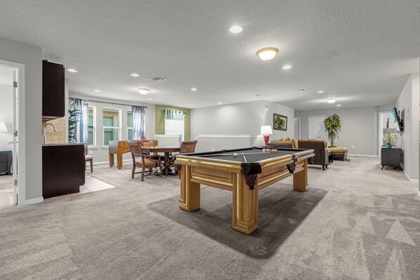 Spacious game room with a pool table and cozy seating—perfect for entertaining and relaxation.