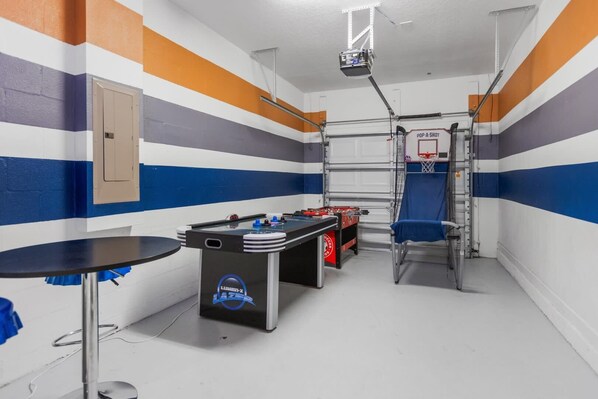 Unleash your competitive spirit in this vibrant game room with air hockey, foosball, and basketball games!