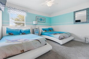 Relax in this serene ocean-themed bedroom with cozy beds and calming decor, perfect for a peaceful getaway.