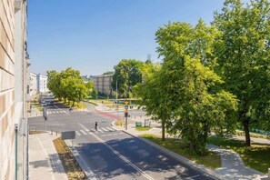 A view of a peaceful, tree-lined street in a sunny urban area, offering a glimpse of greenery and city life.