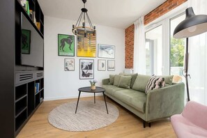 Another angle of the cozy living room with green and pink furniture, enhanced by the open layout and natural light from large windows, creating an airy and inviting space.