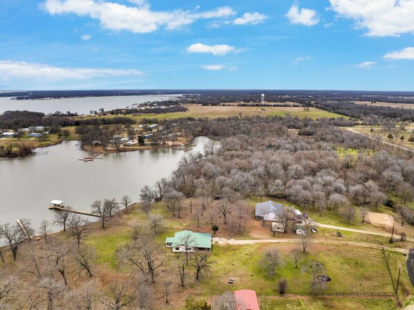 Stunning aerial view of lakefront home with private dock and scenic surroundings