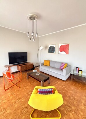 Relax area with double sofa bed, armchairs, bookcase and 55" smart TV with stereo.