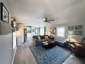 Living room with queen sleeper sofa and ottoman under window with extra bedding.