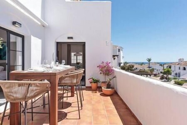 Spacious and illuminated balcony with table, chairs, armchair and table to enjoy a delicious meal.