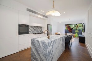 The kitchen features eye-catching designs such as the matching stone splashback and the hanging rope pendant light. 
