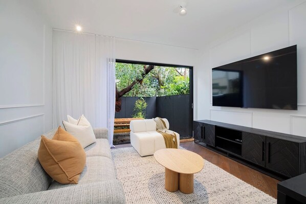 Find your calm in this minimal chic designer lounge room. There are two soft lounges to sink into while watching the ultra-large wall-mounted TV. 
