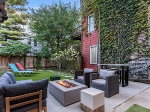 Beautifully landscaped private back yard with fire pit and lounge