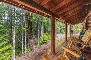 The covered porch with rocking chairs and a view looking out over Pine Ridge is a perfect way to enjoy a morning cup of coffee in the woods