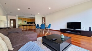 Welcome to the cozy living room of Capelas House by Lovelystay: Features a comfortable sofa, TV, open kitchen, and dining room for a perfect home-away-from-home experience.