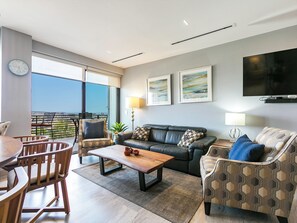 The open-concept living space extends to a balcony, offering both ocean and city views for a perfect blend of indoor and outdoor living.