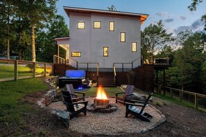 A peek at your private retreat. The firepit, hot tub, and cozy outdoor setup create the perfect space to unwind while taking in the beauty of the home and yard