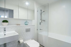 Main bathroom with shower, sink, vanity mirror and bath.