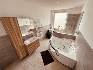 Luxuriöses Badezimmer: Modernes Bad mit einer Whirlwanne, praktischer Dusche und großem Spiegel (1)