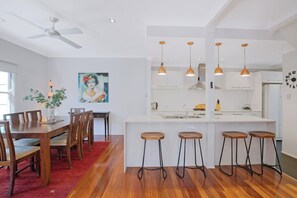 The open-plan dining area features a six-seater table where you can share meals, with additional seating available at the breakfast bar. 
