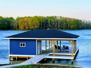 A newly constructed lakeside home with a winding path through freshly landscaped lakeside property leads to a boat house