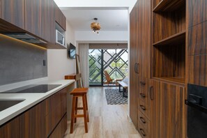 Equipped kitchen, balcony view, and wooden chairs.
