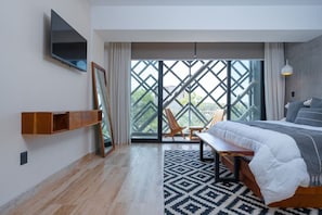 King bed, smart TV, mirror, and balcony with chairs.