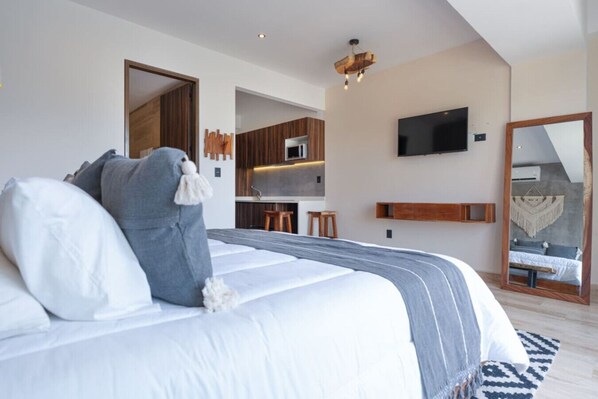 King bed, TV, kitchenette, mirror, and warm modern design.