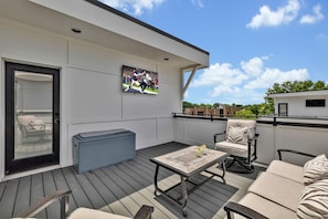4th Floor: Private rooftop patio featuring outdoor furnishings for lounging and a Smart TV for entertainment surrounded by beautiful neighborhood views.