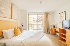 Unwind in this inviting bedroom, featuring a comfortable bed, a spacious desk area, and a touch of natural light.
