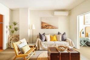 This welcoming living space, which has warm couches, an armchair, and some natural light, is a great place to unwind.