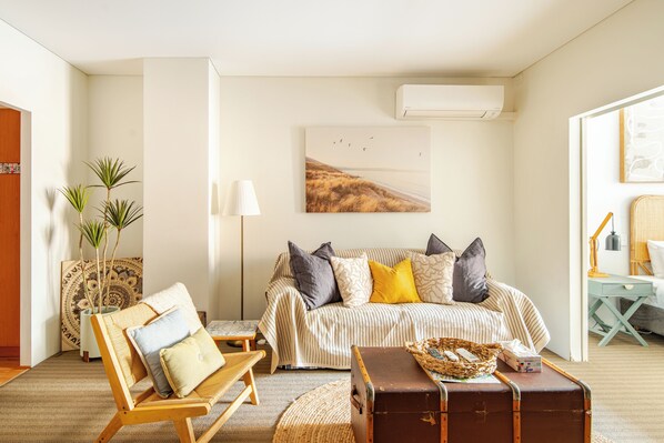 This welcoming living space, which has warm couches, an armchair, and some natural light, is a great place to unwind.