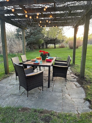 Formal dining area under pergola during daytime. Seats 8 total with two grills!