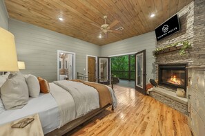 You'll love this luxurious master ensuite downstairs, featuring a TV, fireplace, & double doors leading to a patio with a cozy outdoor sofa perfect for 2. Enjoy storage with a convenient chest for your clothing, along with an attached full bathroom