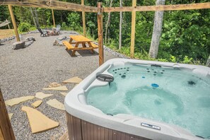 Hot tub seats 6-7 people with privacy fence and string lights.