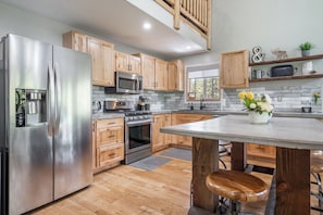 This beautifully designed kitchen blends rustic charm with modern convenience, featuring stainless steel appliances, a spacious island, and warm wood cabinetry.
