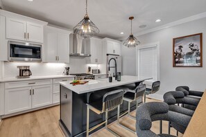 2nd Floor: Fully equipped kitchen stocked with all culinary essentials featuring Monogram stainless-steel appliances, a large kitchen island offering bar seating.