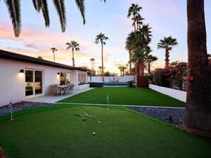 Private backyard featuring a pool, hot tub, BBQ grill, lounge chairs, mini golf, and a patio with a Smart TV, fire pit and outdoor dining area that seats 6 guests.