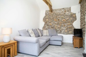 Living room with corner sofa, TV and feature stone walls