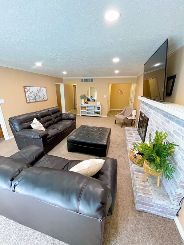 Spacious living room featuring leather couches and large screen smart TV