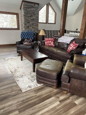 Large living area with vaulted ceilings, fireplace, and large windows.