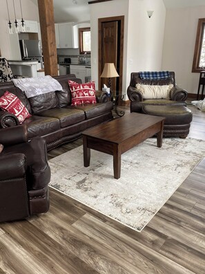 Large living area with vaulted ceilings, fireplace, and large windows.