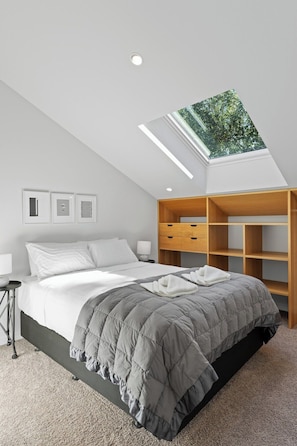 Queen bed with a skylight and loads of shelving